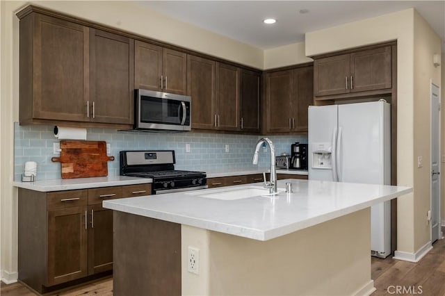 4271 Horvath St Unit 103, Corona, CA 92883 - kitchen with stainless steel appliances, dark brown cabinetry, wood finished floors, decorative backsplash, and recessed lighting