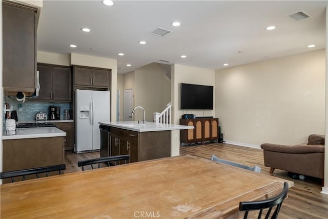 4271 Horvath St Unit 103, Corona, CA 92883 - kitchen with white refrigerator with ice dispenser, open floor plan, dark brown cabinetry, a center island with sink, and recessed lighting