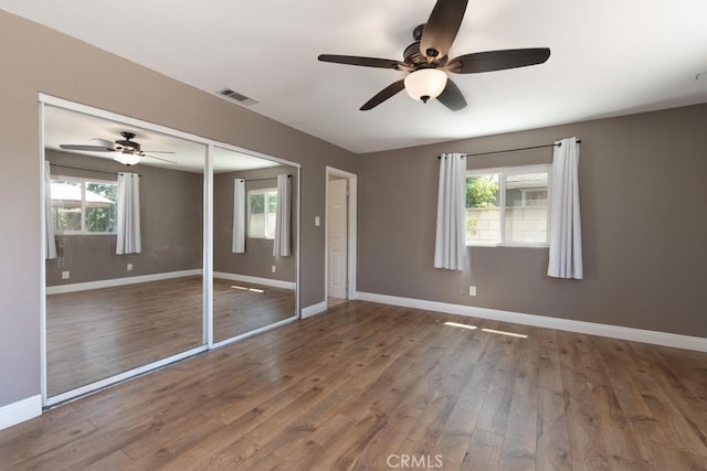 4356 Gardena Dr, Riverside, CA 92506 - unfurnished bedroom featuring multiple windows, wood finished floors, a ceiling fan, and a closet