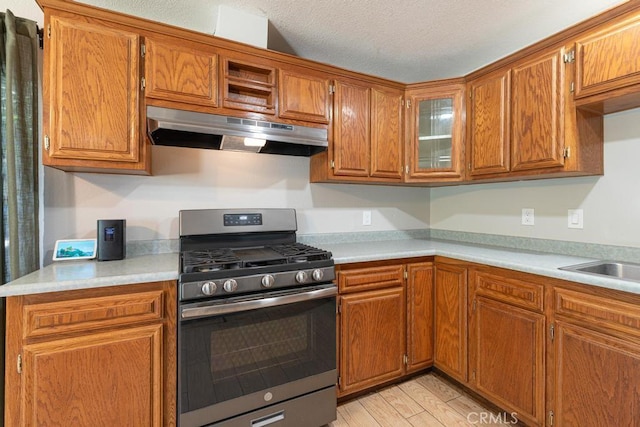 4356 Gardena Dr, Riverside, CA 92506 - kitchen featuring stainless steel gas stove, under cabinet range hood, brown cabinetry, light countertops, and a textured ceiling