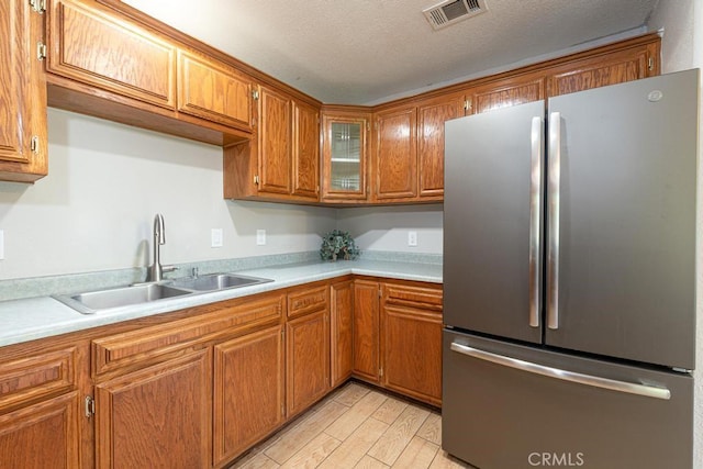 4356 Gardena Dr, Riverside, CA 92506 - kitchen with freestanding refrigerator, light countertops, brown cabinets, and light wood-type flooring