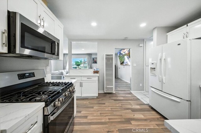 149 S Mistletoe Ave, San Jacinto, CA 92583 - kitchen with stainless steel appliances, a heating unit, light wood-style floors, white cabinets, and light stone countertops