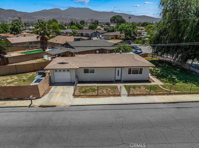 149 S Mistletoe Ave, San Jacinto, CA 92583 - view of front of home featuring a fenced front yard, a garage, a mountain view, concrete driveway, and a residential view