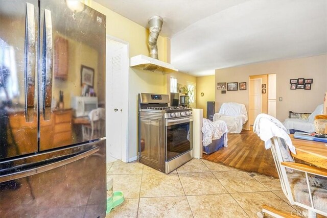 9130 Hargill, Bellflower, CA 90706 - kitchen with freestanding refrigerator, gas stove, light tile patterned floors, wall chimney range hood, and open floor plan