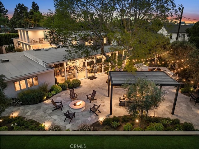 2301 Santiago Dr, Newport Beach, CA 92660 - back of property at dusk with an outdoor fire pit, a patio area, and stucco siding