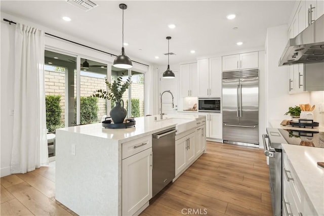 4836 Arroyo Run, Moorpark, CA 93021 - kitchen featuring built in appliances, under cabinet range hood, white cabinets, light wood-type flooring, and an island with sink