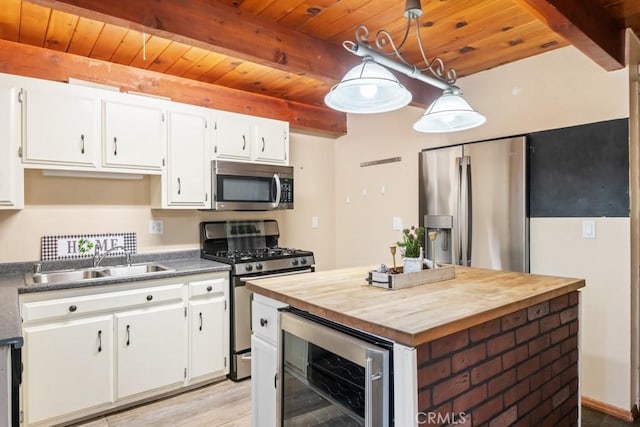 2616 Secret Dr, Running Springs, CA 92382 - kitchen with stainless steel appliances, wine cooler, butcher block countertops, a wood ceiling with exposed beams, and white cabinetry