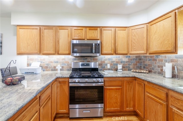 10838 Burnet Ave, San Fernando, CA 91345 - kitchen with appliances with stainless steel finishes, light stone counters, decorative backsplash, and light wood-style flooring