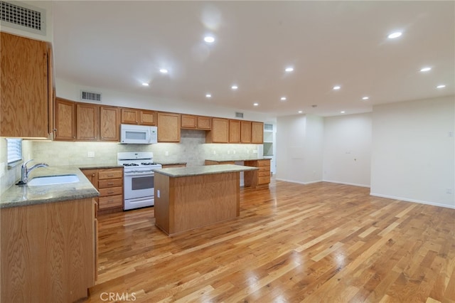 10838 Burnet Ave, San Fernando, CA 91345 - kitchen with white appliances, a kitchen island, tasteful backsplash, light wood-style floors, and recessed lighting