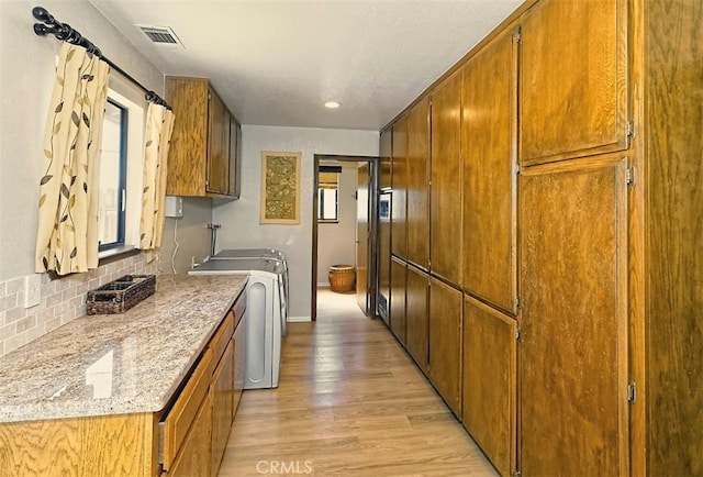 15381 Otomian Rd, Apple Valley, CA 92307 - kitchen with light wood-style floors, brown cabinetry, tasteful backsplash, washer / dryer, and recessed lighting