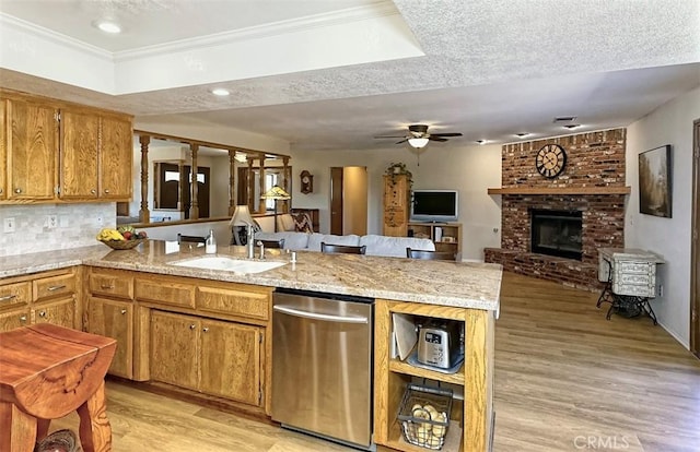 15381 Otomian Rd, Apple Valley, CA 92307 - kitchen featuring dishwasher, a peninsula, light wood-style floors, brown cabinets, and a fireplace