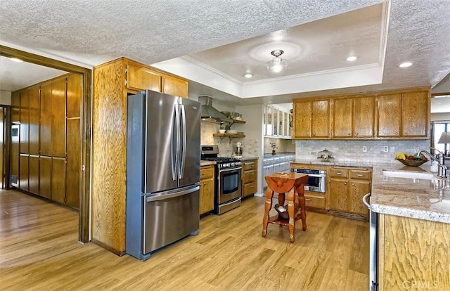15381 Otomian Rd, Apple Valley, CA 92307 - kitchen with appliances with stainless steel finishes, a raised ceiling, wall chimney range hood, a textured ceiling, and light wood-style flooring