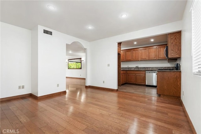 7137 Shoup Ave Unit 39, West Hills, CA 91307 - kitchen featuring stainless steel appliances, brown cabinetry, dark countertops, arched walkways, and light wood-style flooring