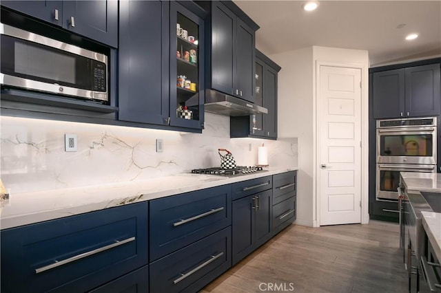 19680 Griffith Dr, Saugus, CA 91350 - kitchen with appliances with stainless steel finishes, tasteful backsplash, wood finished floors, glass insert cabinets, and under cabinet range hood