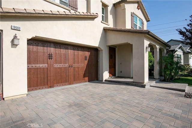 19680 Griffith Dr, Saugus, CA 91350 - view of exterior entry with stucco siding, a garage, a tile roof, and driveway