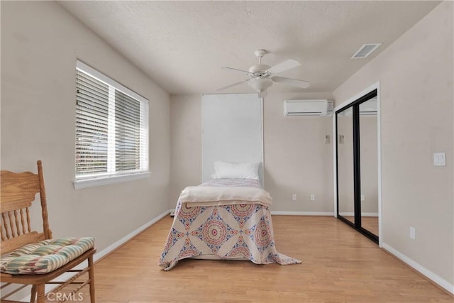 14908 Dakota Rd, Apple Valley, CA 92307 - bedroom featuring a wall mounted air conditioner, light wood-type flooring, and a ceiling fan