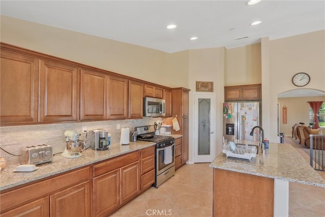 32124 Evening Primrose Trl, Campo, CA 91906 - kitchen featuring stainless steel appliances, tasteful backsplash, brown cabinetry, light stone countertops, and a towering ceiling