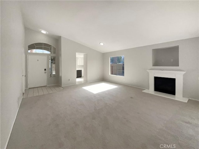 995 Northpark Blvd, San Bernardino, CA 92407 - unfurnished living room featuring a fireplace with raised hearth, carpet, lofted ceiling, and healthy amount of natural light