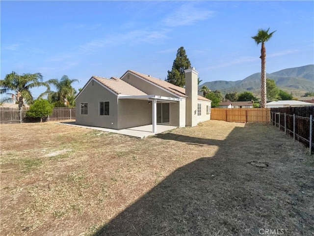 995 Northpark Blvd, San Bernardino, CA 92407 - back of house with a mountain view, a fenced backyard, stucco siding, and a tile roof