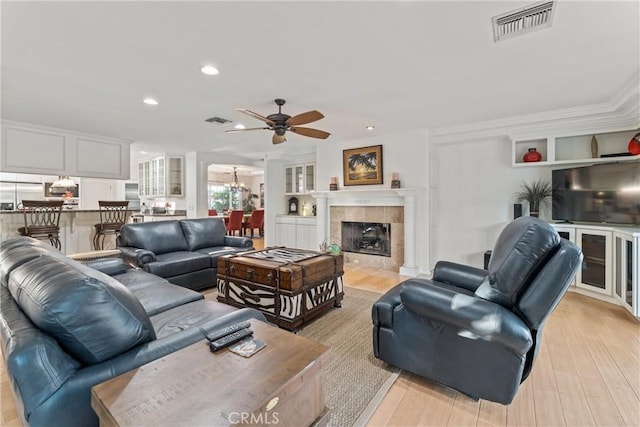 6720 Sycamore Ln, Palmdale, CA 93551 - living room with a ceiling fan, light wood-style floors, recessed lighting, a tile fireplace, and crown molding