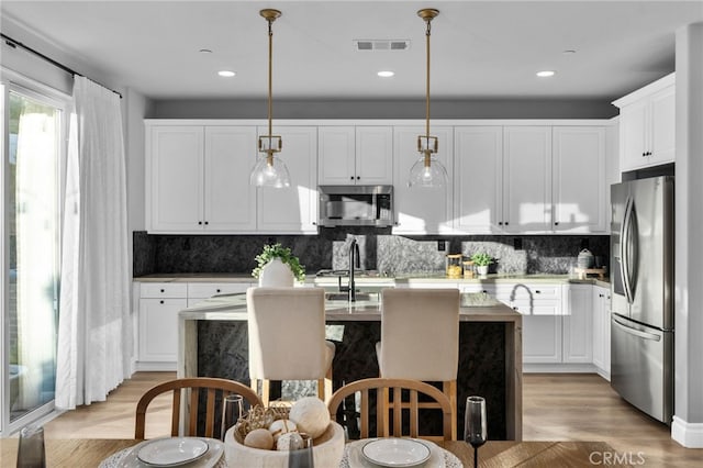11824 Stonefield Dr, Corona, CA 92883 - kitchen with stainless steel appliances, a kitchen island with sink, tasteful backsplash, white cabinetry, and recessed lighting