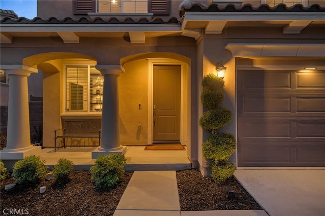 11824 Stonefield Dr, Corona, CA 92883 - view of exterior entry with a tile roof, a porch, stucco siding, and a garage