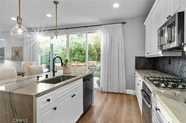 11824 Stonefield Dr, Corona, CA 92883 - kitchen with stainless steel appliances, decorative backsplash, white cabinets, a center island with sink, and light wood-type flooring