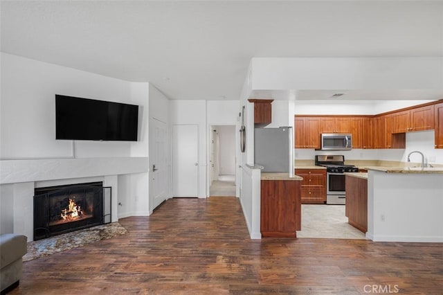 4822 Tiara Dr Unit 104, Huntington Beach, CA 92649 - kitchen with appliances with stainless steel finishes, open floor plan, wood finished floors, a premium fireplace, and brown cabinets