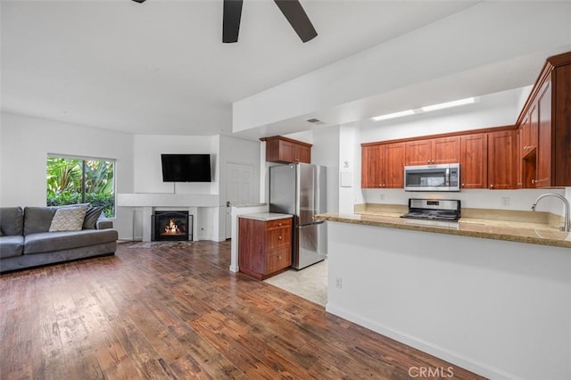4822 Tiara Dr Unit 104, Huntington Beach, CA 92649 - kitchen with appliances with stainless steel finishes, ceiling fan, light wood-type flooring, a warm lit fireplace, and open floor plan