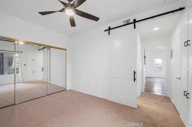 4822 Tiara Dr Unit 104, Huntington Beach, CA 92649 - unfurnished bedroom featuring a barn door, light carpet, a closet, and ceiling fan