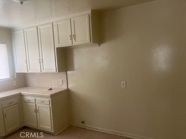 13419 Gridley Rd, Norwalk, CA 90650 - kitchen with tile counters, white cabinets, and backsplash