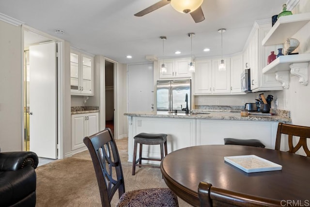 999 N Pacific St Unit A208, Oceanside, CA 92054 - kitchen with appliances with stainless steel finishes, a peninsula, white cabinetry, ceiling fan, and light stone countertops