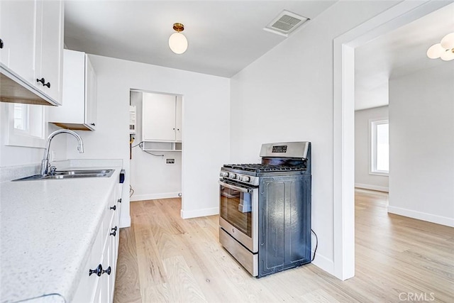 708 S Redondo Ave, Manhattan Beach, CA 90266 - kitchen featuring stainless steel gas range oven, light wood-style flooring, white cabinetry, and light countertops