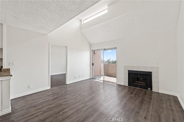 450 E 4th St Unit 419, Santa Ana, CA 92701 - unfurnished living room with vaulted ceiling, a tile fireplace, dark wood-style flooring, and a textured ceiling