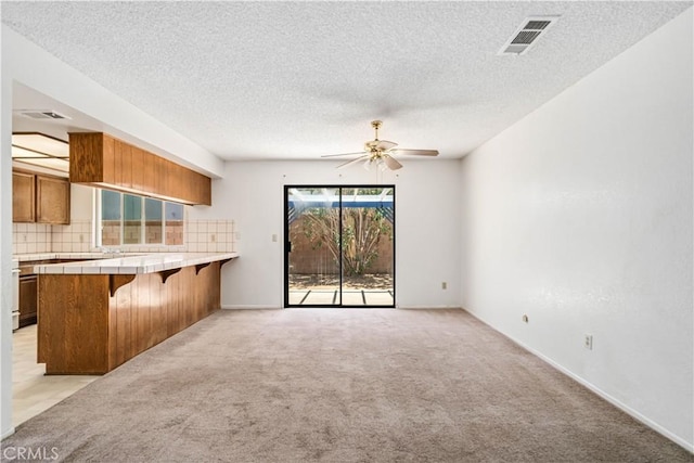 37224 Halfmoon Dr, Palmdale, CA 93550 - kitchen with tile counters, a breakfast bar area, light carpet, brown cabinets, and ceiling fan