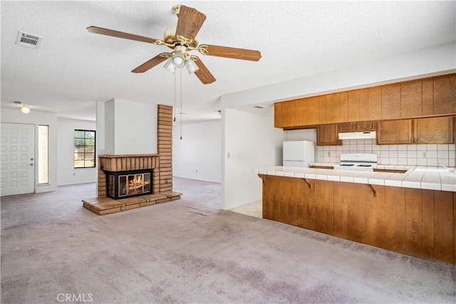 37224 Halfmoon Dr, Palmdale, CA 93550 - kitchen with freestanding refrigerator, tile counters, brown cabinets, stove, and under cabinet range hood