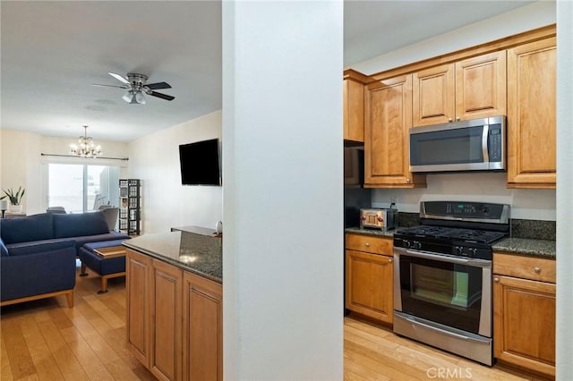 2750 Artesia Blvd Unit 313, Redondo Beach, CA 90278 - kitchen with stainless steel appliances, light wood finished floors, a chandelier, a ceiling fan, and dark stone countertops