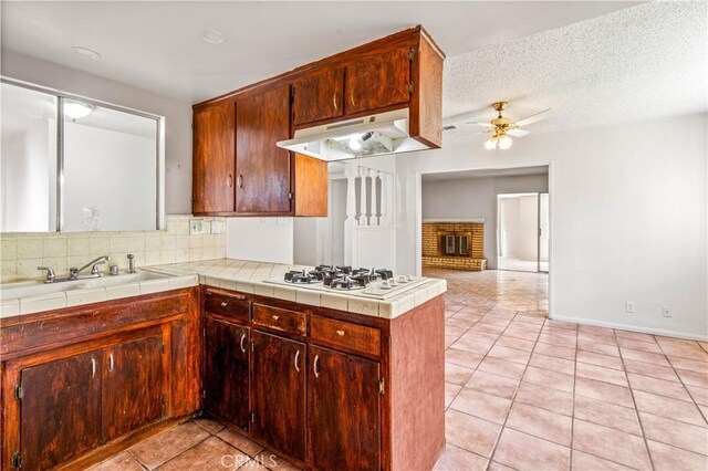 43236 W 20th St W, Lancaster, CA 93534 - kitchen with white gas stovetop, under cabinet range hood, light tile patterned floors, a ceiling fan, and decorative backsplash