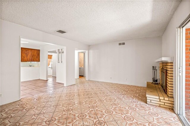 43236 W 20th St W, Lancaster, CA 93534 - unfurnished living room featuring a brick fireplace, a textured ceiling, and light tile patterned floors