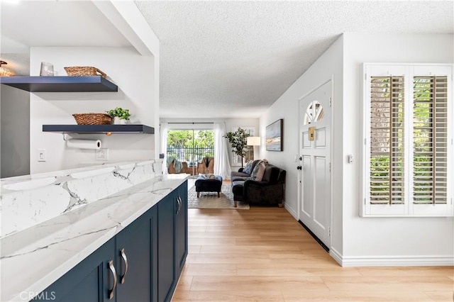 1442 Brett Pl Unit 31, San Pedro, CA 90732 - kitchen featuring blue cabinets, light wood-style floors, a textured ceiling, light stone countertops, and open shelves