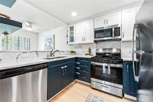 1442 Brett Pl Unit 31, San Pedro, CA 90732 - kitchen with stainless steel appliances, blue cabinets, white cabinetry, decorative backsplash, and light wood finished floors