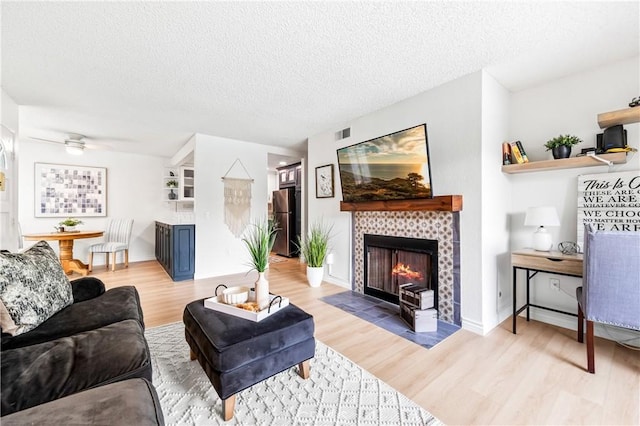 1442 Brett Pl Unit 31, San Pedro, CA 90732 - living room with light wood finished floors, a fireplace, a textured ceiling, and a ceiling fan