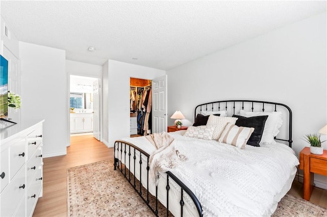 1442 Brett Pl Unit 31, San Pedro, CA 90732 - bedroom with light wood-style flooring, a spacious closet, a closet, connected bathroom, and a textured ceiling
