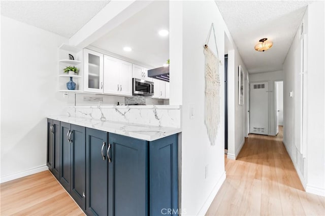 1442 Brett Pl Unit 31, San Pedro, CA 90732 - kitchen featuring stainless steel microwave, open shelves, light wood finished floors, white cabinets, and decorative backsplash