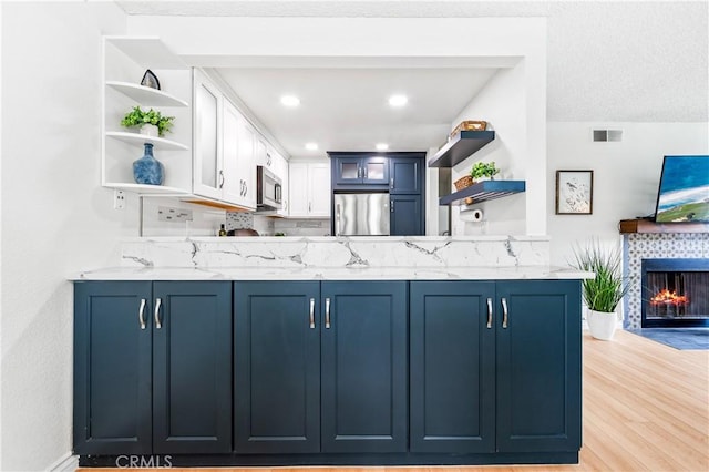 1442 Brett Pl Unit 31, San Pedro, CA 90732 - kitchen with open shelves, refrigerator, stainless steel microwave, blue cabinetry, and a fireplace
