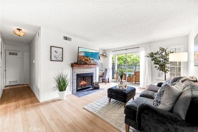 1442 Brett Pl Unit 31, San Pedro, CA 90732 - living room featuring a textured ceiling, a tile fireplace, and light wood finished floors