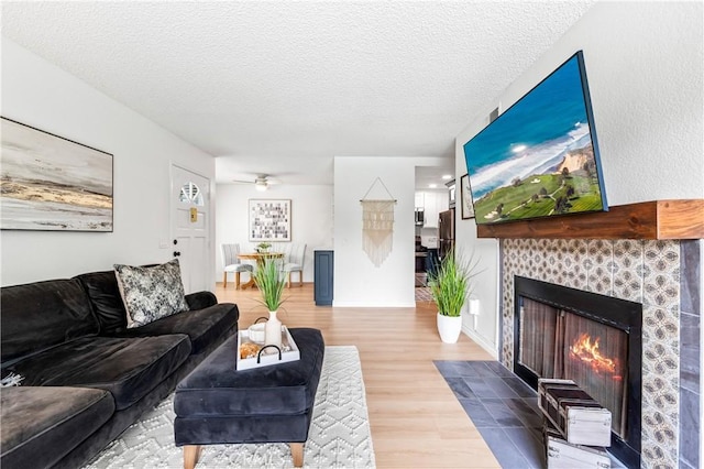 1442 Brett Pl Unit 31, San Pedro, CA 90732 - living room with wood finished floors, a tiled fireplace, a textured ceiling, and ceiling fan