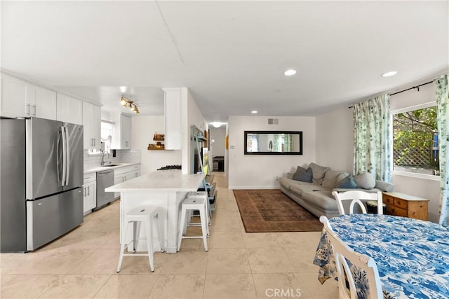 4054 Lewis St, Oceanside, CA 92056 - kitchen featuring appliances with stainless steel finishes, light countertops, a breakfast bar, tasteful backsplash, and white cabinetry