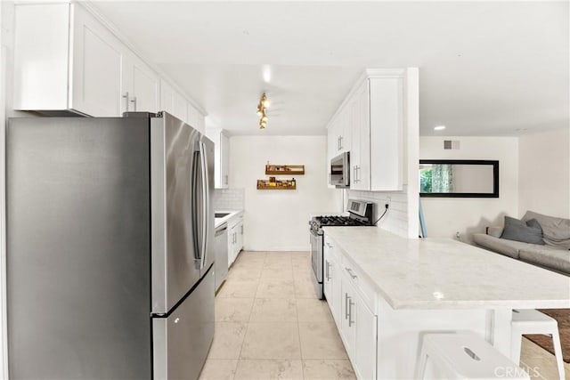 4054 Lewis St, Oceanside, CA 92056 - kitchen with stainless steel appliances, backsplash, a peninsula, white cabinetry, and open floor plan