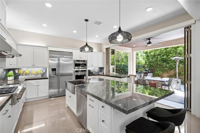 131 Spiral, Irvine, CA 92618 - kitchen featuring appliances with stainless steel finishes, backsplash, white cabinetry, a kitchen breakfast bar, and recessed lighting